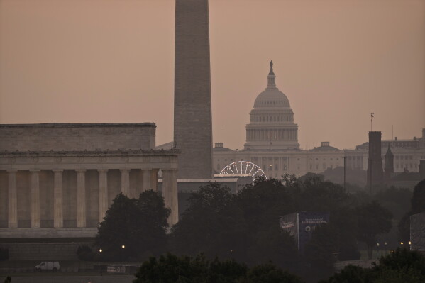 The Lincoln Memorial, the Washington Monument, and the U.S. Capitol, are seen at dawn from an overlook in Arlington, Va., as Washington prepares for sweltering temperatures, Friday, July 3, 2026. (AP Photo/J. Scott Applewhite)