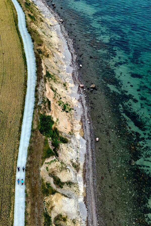 People ride their bikes along the eroding cliff coast of the Baltic Sea in Brodten, Germany, Friday, July 10, 2026. (AP Photo/Michael Probst)