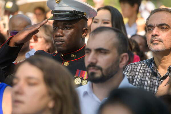 U.S. Marine Sgt. Diakaria Sangare, center, from Guinea, salutes the playing of the national anthem at a naturalization ceremony on Independence Day at George Washington's Mount Vernon, Saturday, July 4, 2026, in Alexandria, Va. (AP Photo/Rod Lamkey, Jr.)