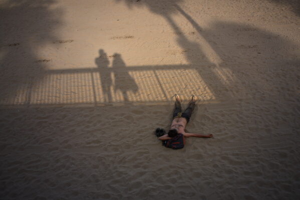 A man sleeps on a beach in Barcelona, Spain, Monday, July 13, 2026. (AP Photo/Emilio Morenatti)