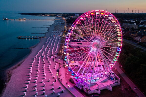 A Ferris wheel is illuminated at the beach on the Baltic Sea in Groemitz, Germany, Friday, July 10, 2026. (AP Photo/Michael Probst)