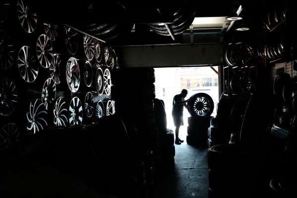 Eric Hood Jr., works on a tire at Hood's Tire Services in the extreme hot weather Tuesday, July 14, 2026, in Detroit. (AP Photo/Paul Sancya)