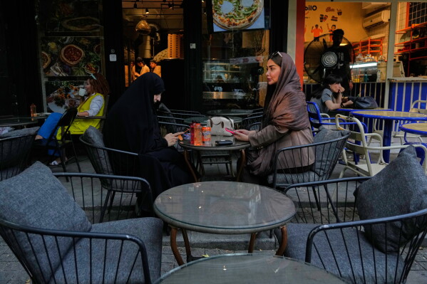 People sit at the outside areas of cafes in northern Tehran, Iran, Monday, July 13, 2026. (AP Photo/Vahid Salemi)