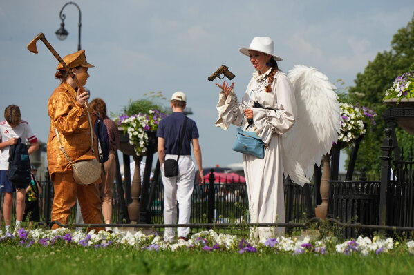 A street performer wearing an angel costume plays with a toy gun in central St. Petersburg, Russia, Wednesday, July 15, 2026. (AP Photo/Dmitri Lovetsky)