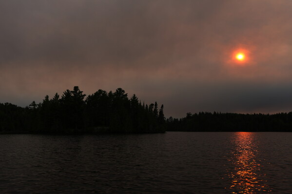 Thick smoke from the Camp Fire hangs in the air over Moose Lake as multiple wildfires burning in the Boundary Waters Canoe Area Wilderness prompted its closure and evacuation Tuesday, July 14, 2026 in Ely, Minn. (Anthony Souffle/Minnesota Star Tribune via AP)