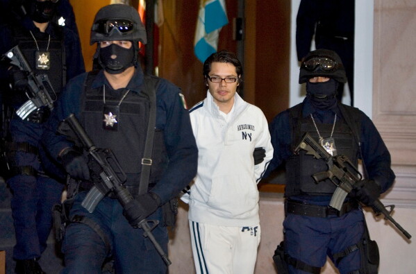 Federal police officers escort Vicente Carrillo Leyva, the alleged second-in-command of the Juarez Cartel, during his presentation to the media in Mexico City, April 2, 2009. (AP Photo/Eduardo Verdugo, File)