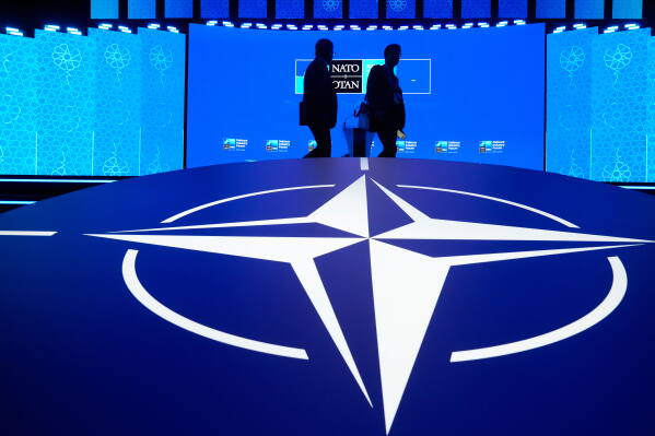 Two men walk past the NATO logo during the NATO Defense Industry Forum at the NATO summit in Ankara, Turkey, Tuesday, July 7, 2026. (AP Photo/Hussein Malla)