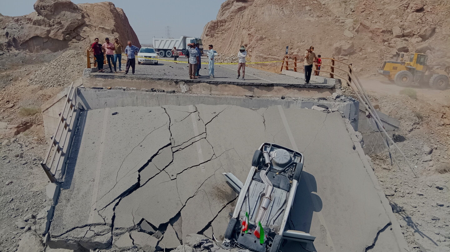 An overturned car sits on a section of a destroyed bridge after a strike in Hormozgan province, southern Iran, July 18, 2026. (Mahdi Negahban/Mehr News Agency via AP)