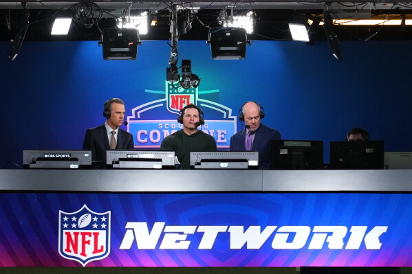 Seattle Seahawks head coach Mike Macdonald, center, talks on an NFL Network show in Indianapolis, Feb. 26, 2026. (AP Photo/Julio Cortez, File)
