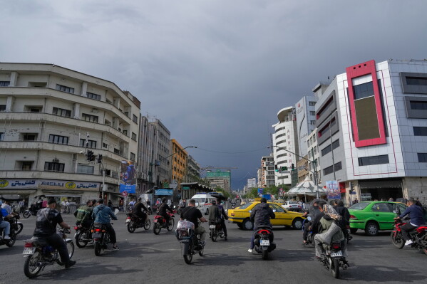 Motorbikes and cars pass through an intersection in downtown Tehran, Iran, May 17, 2026. (AP Photo/Vahid Salemi, File)