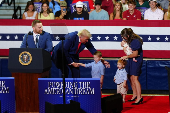 President Donald Trump, center, invites a family on stage to speak about Trump Accounts at Wheeler High School, Wednesday, July 22, 2026, in Marietta, Ga. (AP Photo/Julia Demaree Nikhinson)