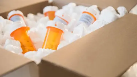 Getty Images Collection of tablets in orange bottles with white tops, contained within a brown cardboard box.