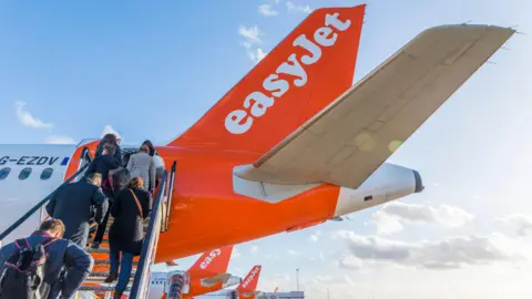 Getty Images People climb steps onto an easyJet plane.