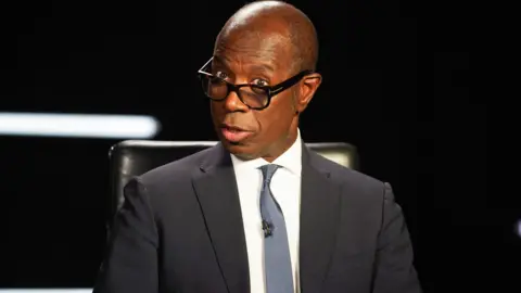 Clive Myrie presenting Mastermind, wearing a suit with a blue tie