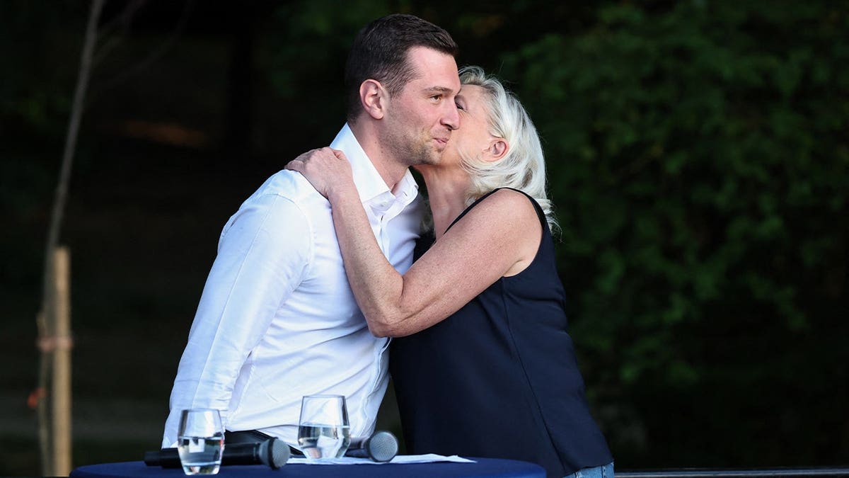 French right-wing party National Rallly (RN) president Jordan Bardella (L) and President of National Rally parliamentary group Marine Le Pen hug as they attend a RN party event
