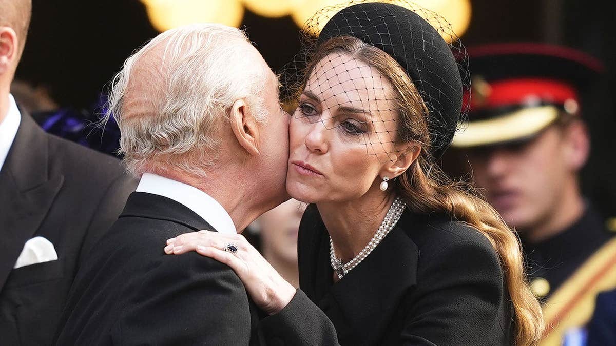 King Charles and Kate Middleton dress in black greeting each other with a kiss on the cheek.