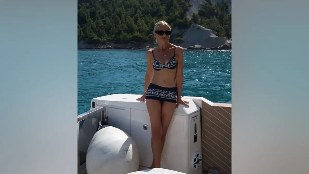 Sarah Michelle Gellar poses aboard a boat wearing a black bikini with white floral detailing, a matching swim skirt and black sunglasses while vacationing in the South of France.