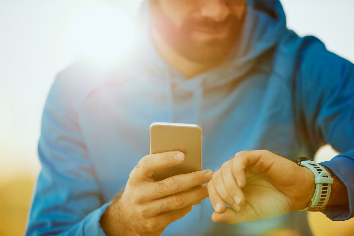 Man with smartphone and fitness tracking watch
