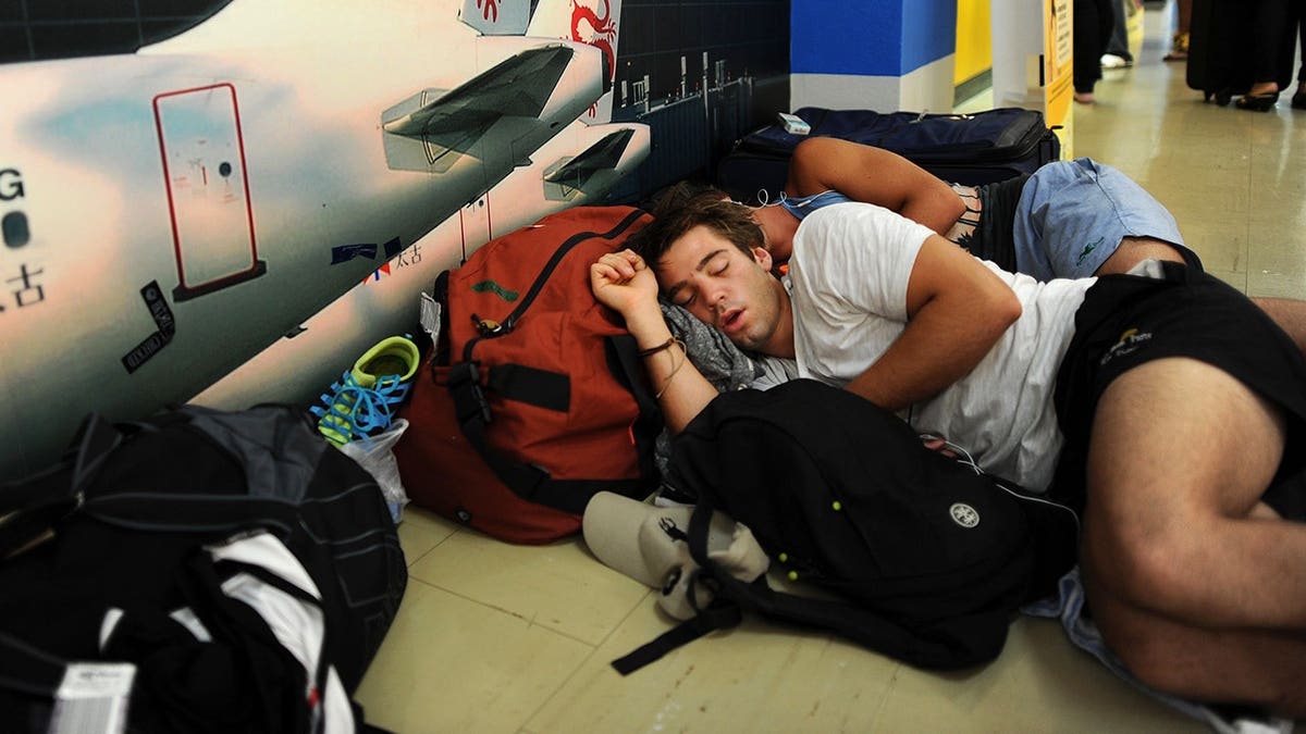 Air Australia passengers sleep with luggage at Phuket International Airport.