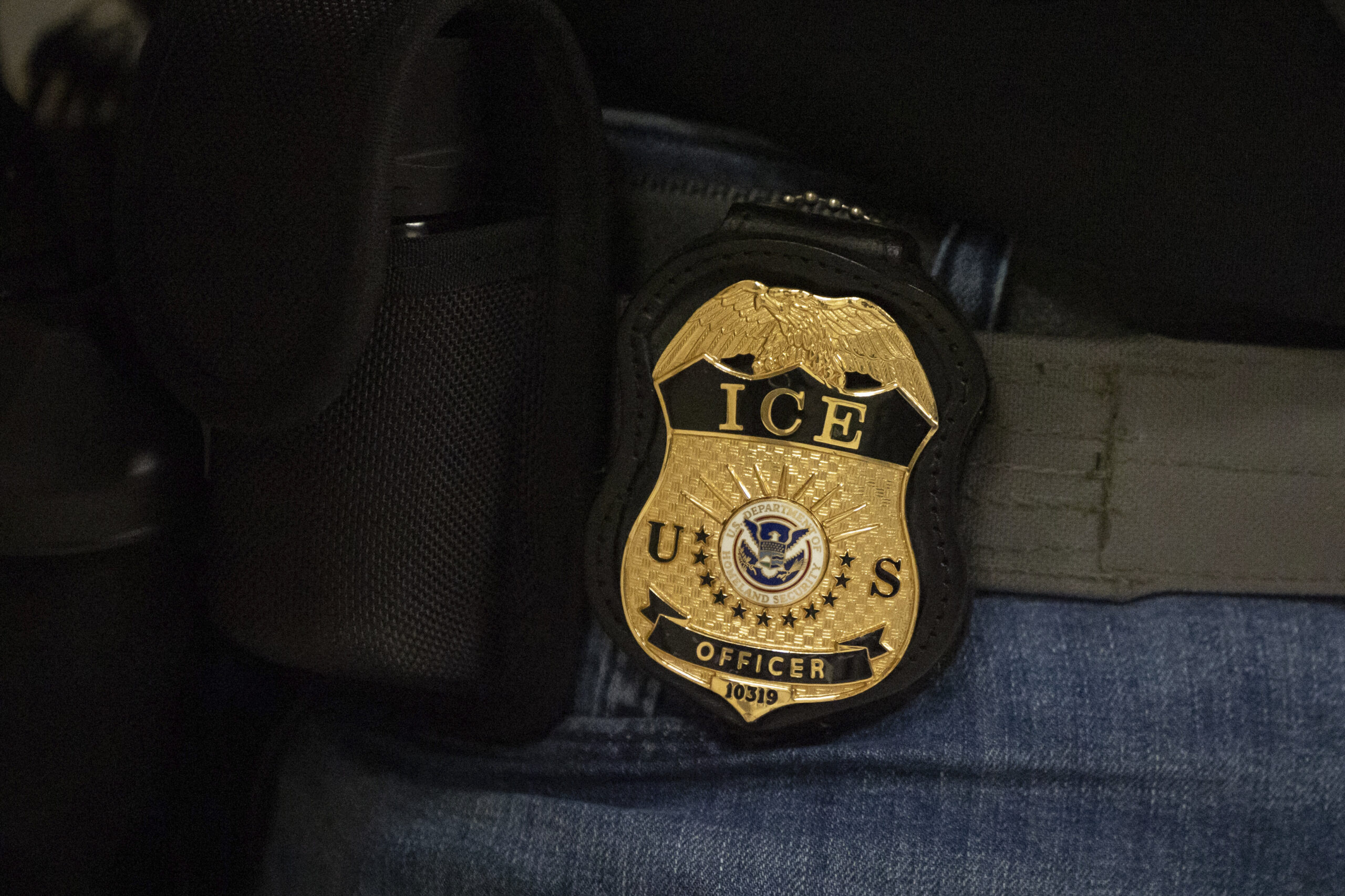 A federal agent wears a badge of Immigration and Customs Enforcement.