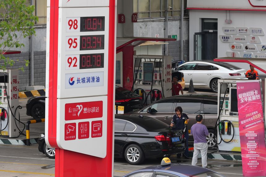 A sign shows fuel prices as motorists fill up fuel tanks at a gas station, in Beijing on May 26, 2026.