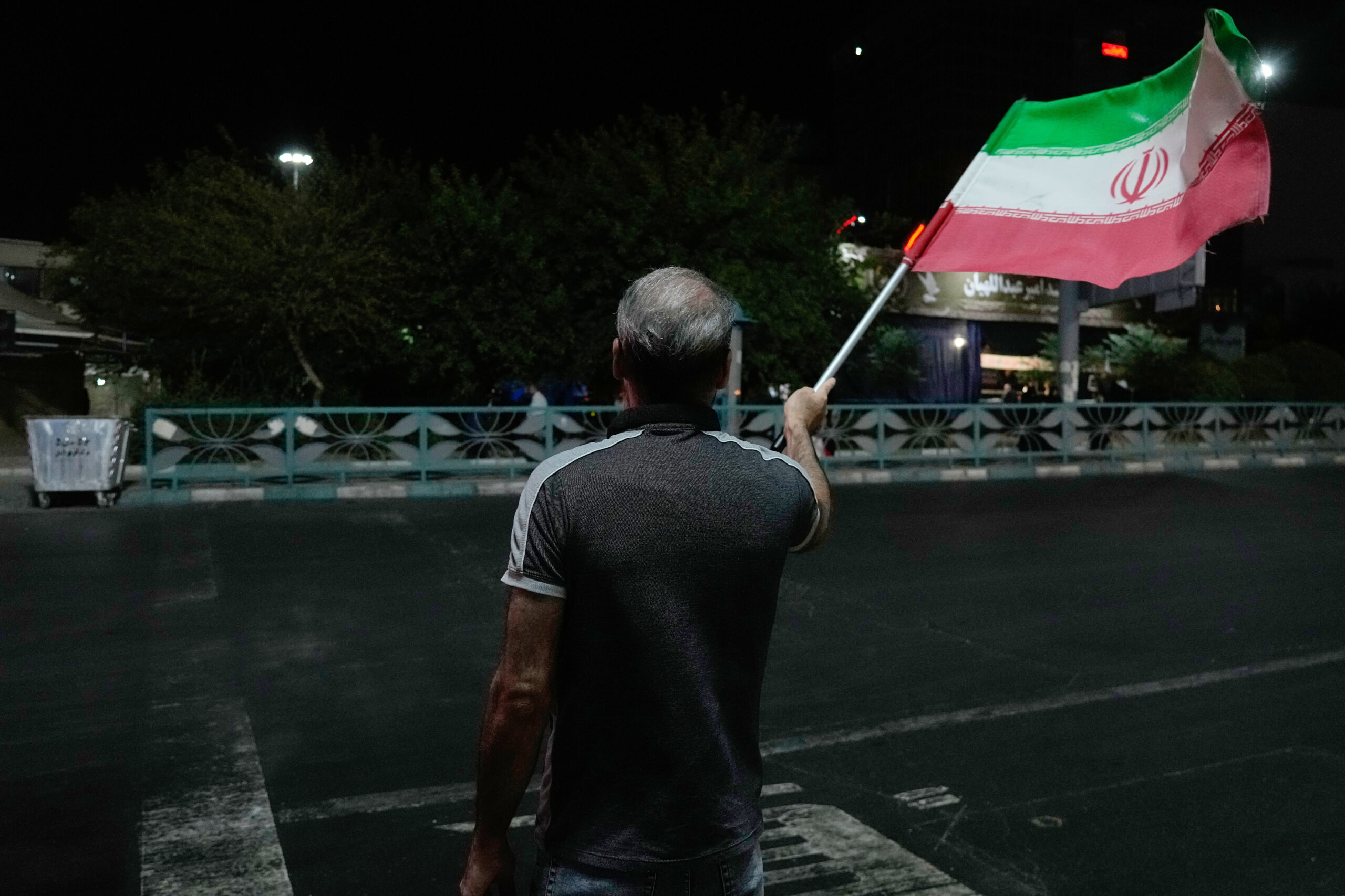 A pro-government demonstrator waves an Iranian flag in a gathering commemorating the late Iranian Supreme Leader Ayatollah Ali Khamenei at a square in Tehran, Iran, Saturday, July 11, 2026.