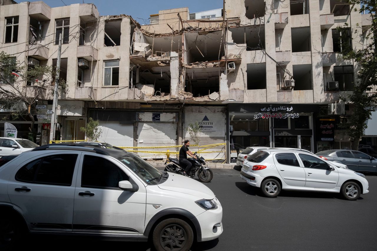 Vehicles and a motorcycle move past a building that was targeted in a US airstrike in Tehran on Tuesday.