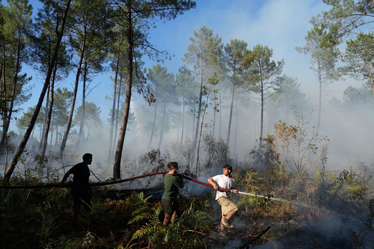A group hold a firehose and try to suppress a fire near Lacanau, as wildfires rage outside Bordeaux, France, on Monday.