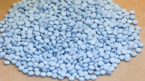 Angela Weiss / AFP via Getty Images A large pile of small blue pills.