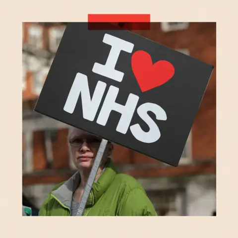 AFP via Getty Images A woman holds a sign which reads I heart NHS