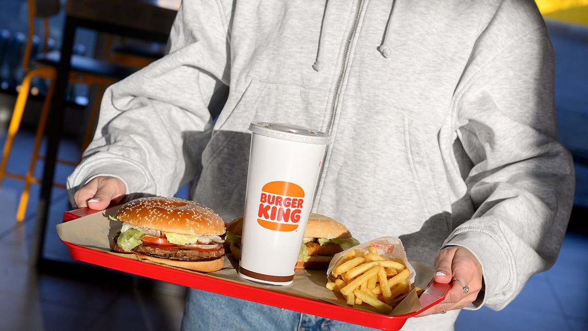 A Burger King customer holds a tray of food.
