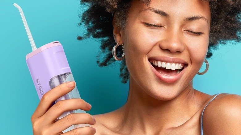 Coslus Mini Water Flosser being held up by a woman