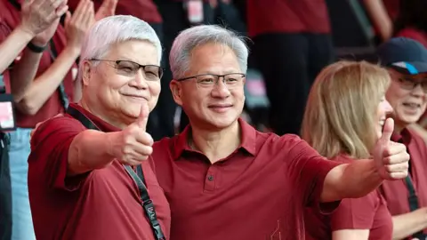 Bloomberg via Getty Images Jensen Huang, chief executive officer of Nvidia (right), poses for photographs with TSMC boss CC Wei smiling with their thumbs up. Both men are dressed in red polo t-shirts