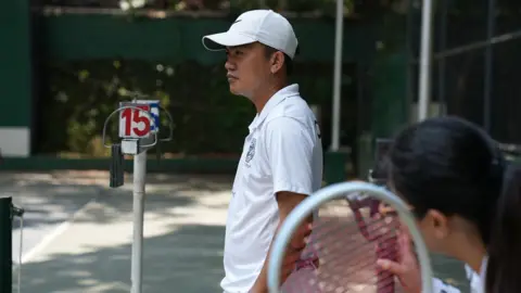 BBC/Virma Simonette Rivera Tennis coach Jovy Barce standing in a tennis court in Manila
