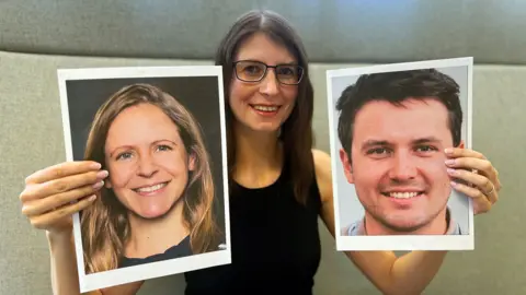 BBC A woman with long dark hair and glasses holds up two large photographs of human faces