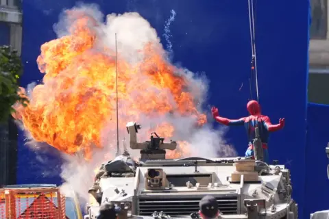 PA Media Spiderman looks to be jumping off a tank as an explosion happens behind him