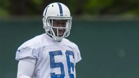 Icon Sportswire via Getty Images He is wearing his American football uniform, but the image is cut just below his shoulders. He is wearing a white helmet with a blue stripe down the middle and a white tshirt with blue detailing