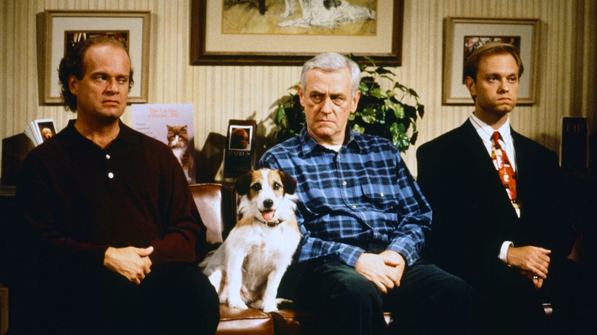 Kelsey Grammer, John Mahoney, David Hyde Pierce and Moose pose together on the Frasier set.