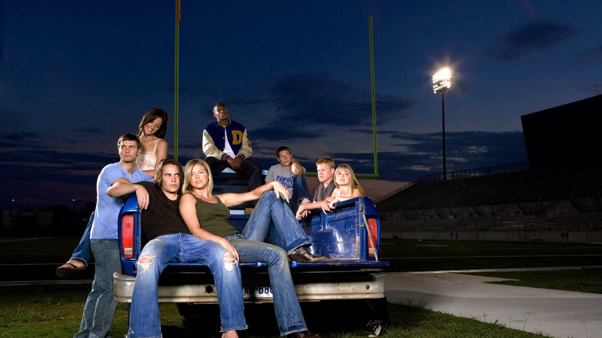 Scott Porter, Minka Kelly, Gaius Charles, Zach Gilford, Jesse Plemons, Aimee Teegarden, Adrianne Palicki, and Taylor Kitsch pose together in a group portrait.