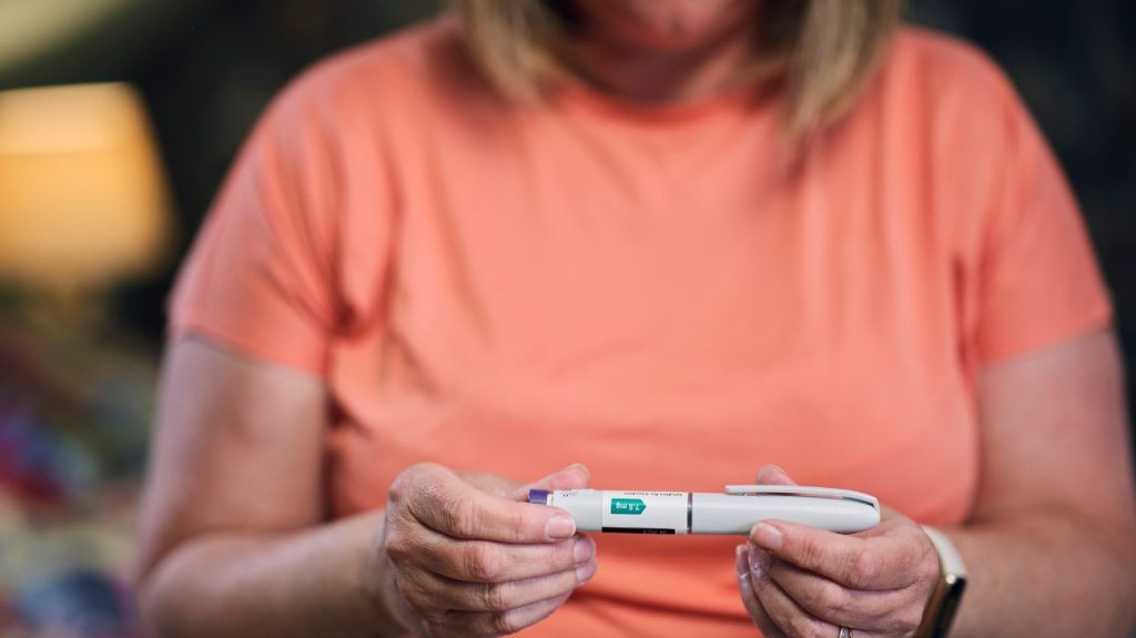 A woman holds a GLP-1 pen used to treat obesity and diabetes in her hands