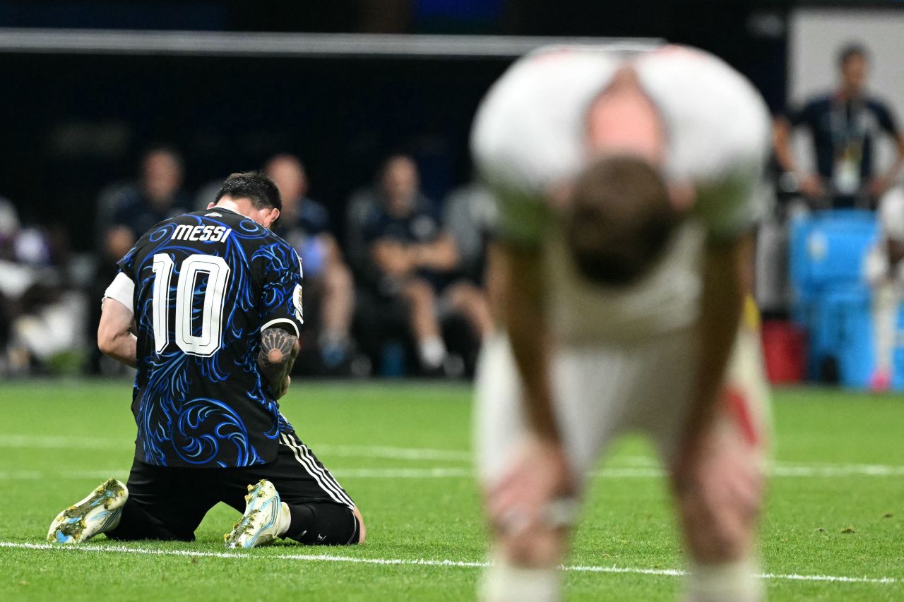 Lionel Messi celebrates as a nearby English player shows his dejection.