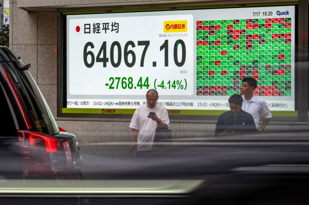 Pedestrians stand in front of an electronic quotation board displaying the Nikkei Stock Average on the Tokyo Stock Exchange on Friday.
