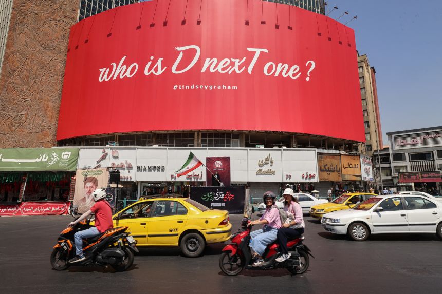 Motorcyclists ride past a huge anti-US billboard referring to the death of US Senator Lindsey Graham at Valiasr Square in Tehran on July 19. The United States said airstrikes on July 19 aimed to "punish" Iran over the first US military deaths since renewed hostilities with the Islamic republic.