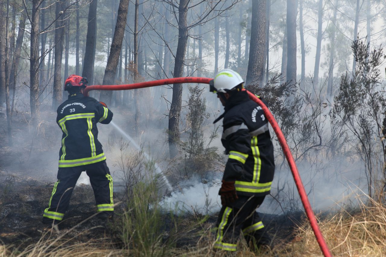 French firefighters spray water to extinguish residual flames and secure the area in a smoke-filled pine forest near Marcheprime during the ongoing Gironde wildfires in southwestern France, on Monday.