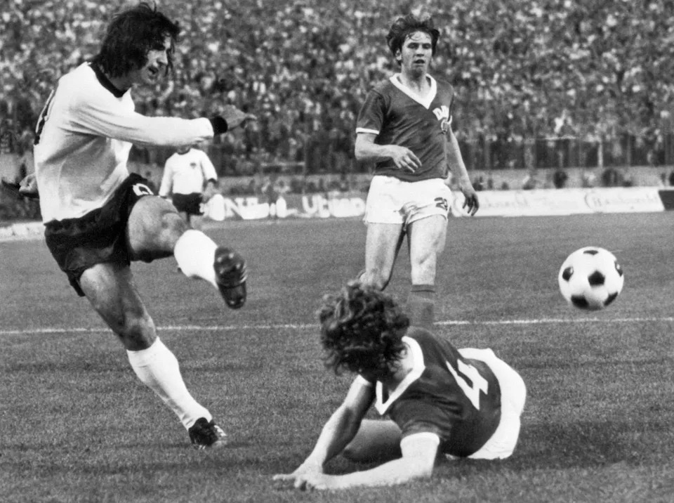 TOPSHOT - West German forward Gerd Müller kicks the ball past East German defender Konrad Weise (4) as forward Martin Hoffmann looks on during the World Cup first round match between East Germany and West Germany 22 June 1974 in Hamburg. East Germany won 1-0 on a goal by forward Juergen Sparwasser. AFP PHOTO (Photo by AFP via Getty Images)