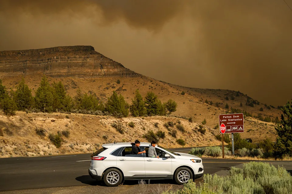 Children watch as the Bench fire approaches on Saturday, July 25, 2026, in Warm Springs, Ore.