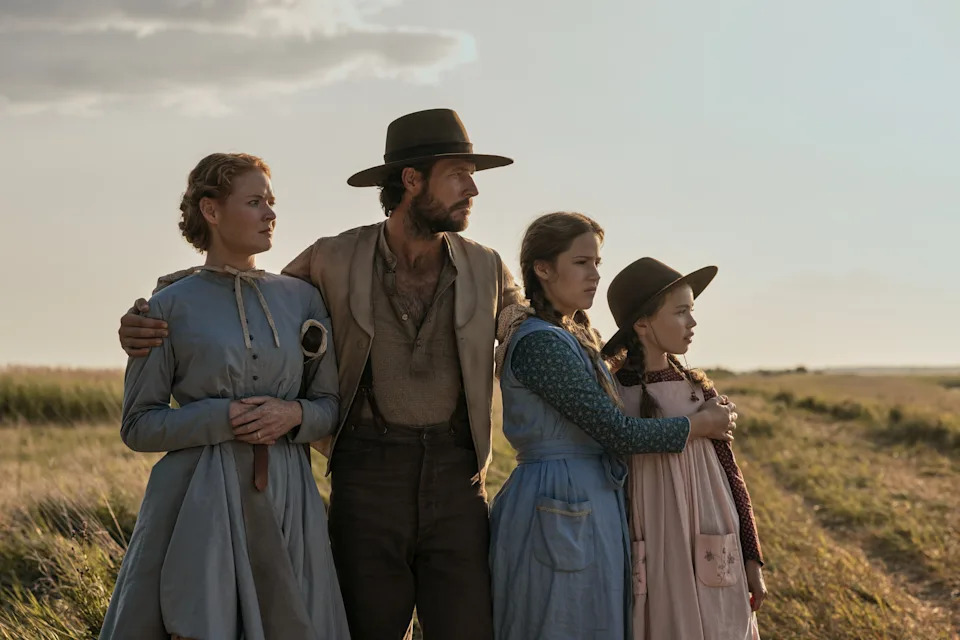 Crosby Fitzgerald as Caroline Ingalls, Luke Bracey as Charles Ingalls, Skywalker Hughes as Mary Ingalls and Alice Halsey as Laura Ingalls in "Little House on the Prairie." A pioneer family stands in a field.