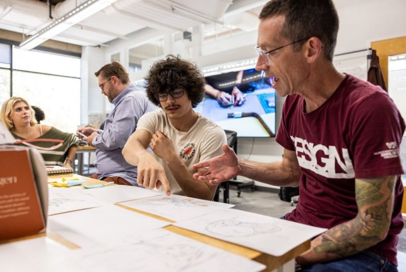 Professor reviews sketches with a student, providing feedback during the speculative design process.