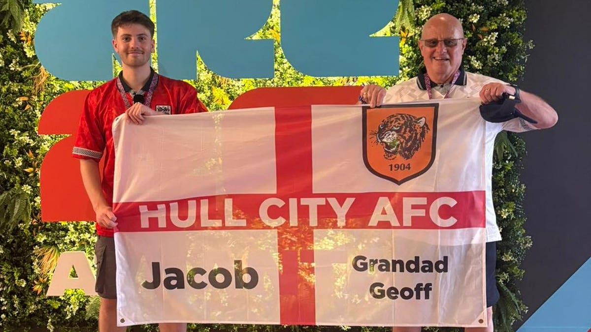 Jacob Allmendinger with grandad Geoff Golliker holding World Cup sign.