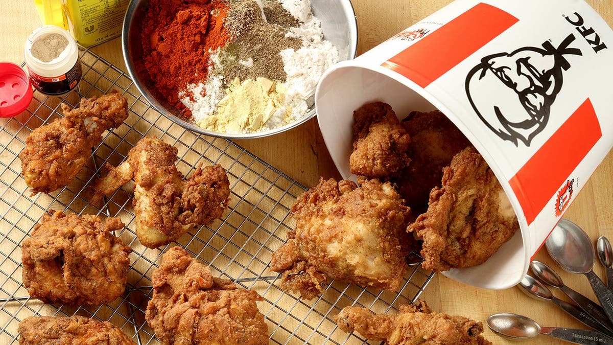 KFC chicken spills out of a bucket with some spices next to it.